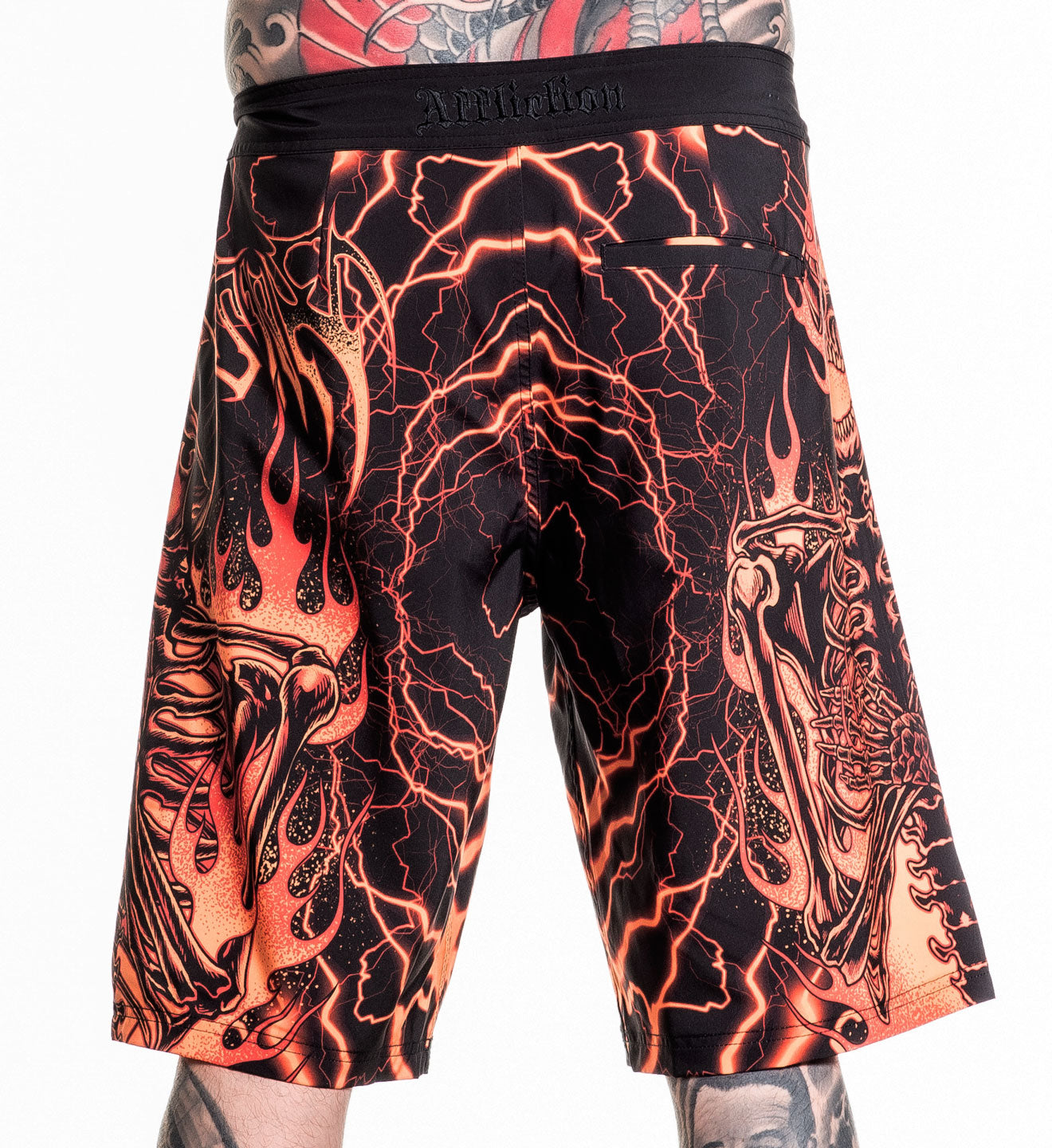 Infernal Nightmare Boardshort with fiery skeleton design in orange and black, made of 92% polyester and 8% spandex stretch fabric.